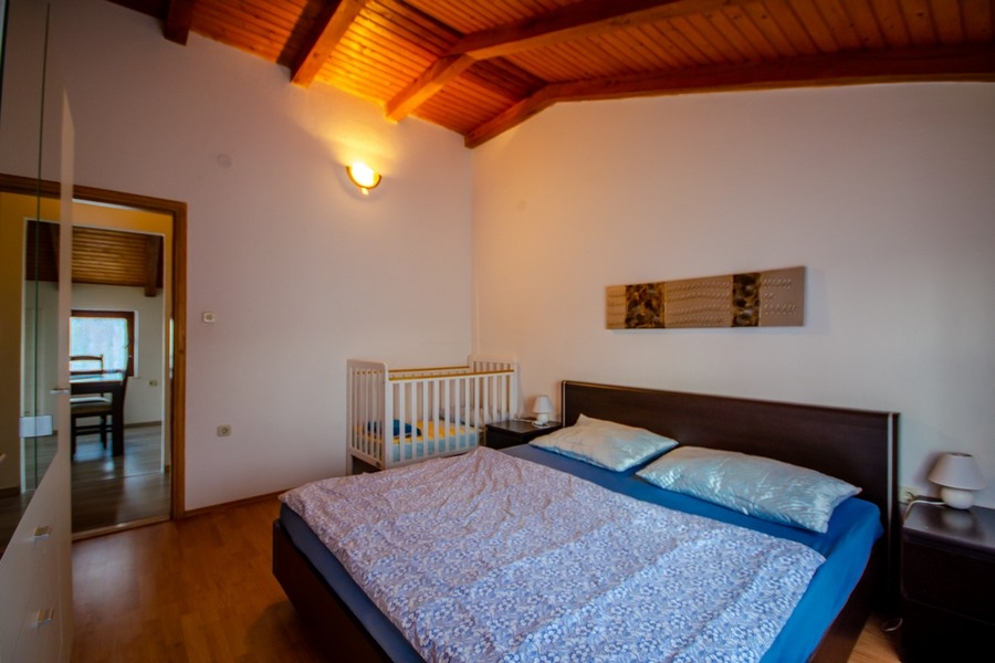 Ložnice s manželskou postelí a trámovým stropem