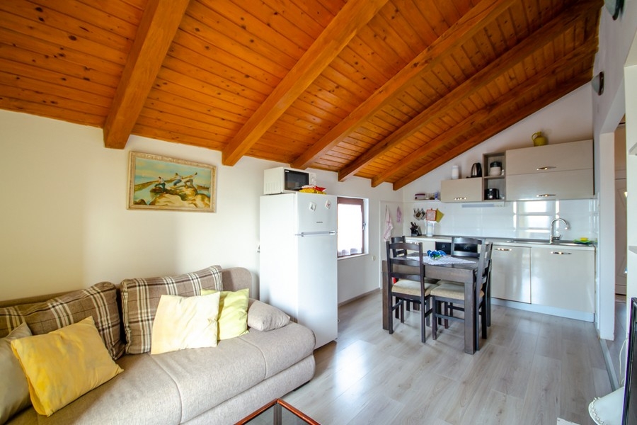 Obývací a jídelní kout s otevřenou kuchyní a dřevěným trámovým stropem