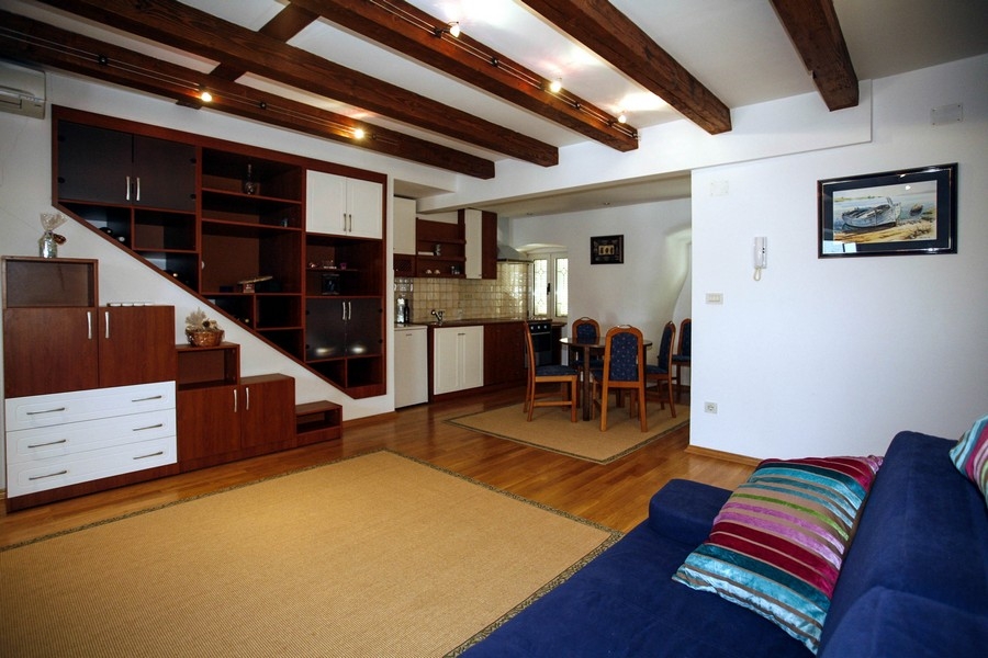 Obývací pokoj s otevřenou kuchyní a odhalenými dřevěnými trámy