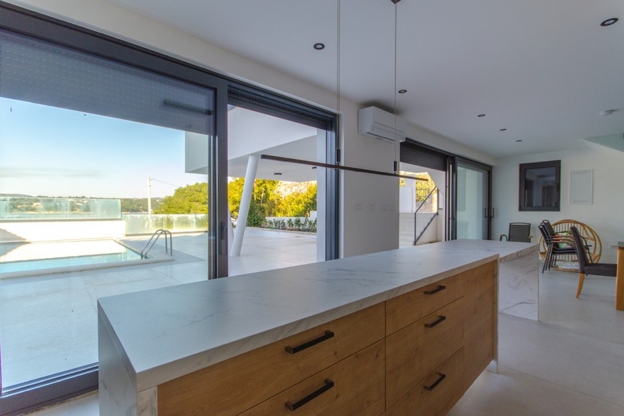 Otevřená kuchyně s výhledem na bazén nemovitosti.