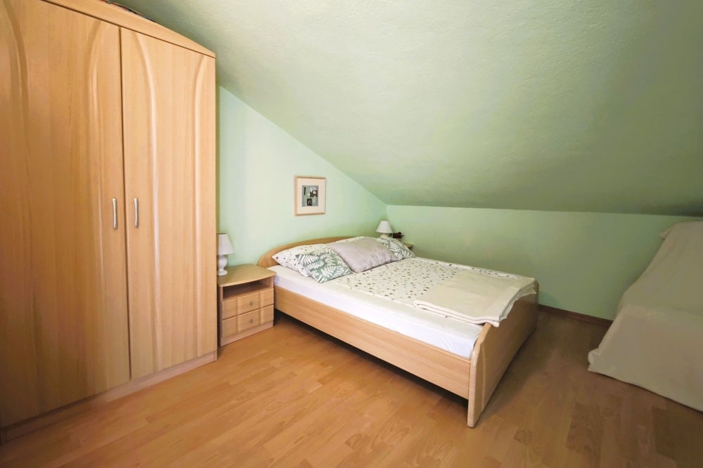 Podkrovní pokoj se zkoseným stropem a samostatným lůžkem