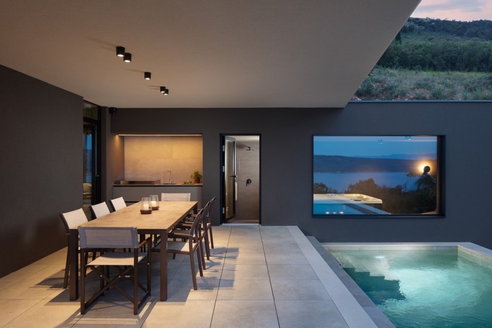 Venkovní prostor s bazénem a krytým jídelním koutem ve večerní atmosféře