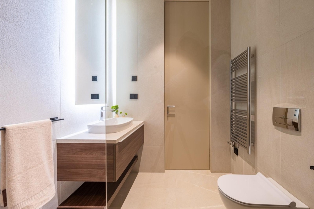 Světlá koupelna s umyvadlem a radiátorem na ručníky