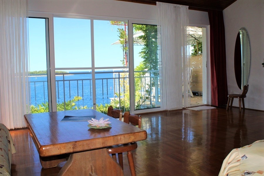 Obývací pokoj s velkými okny a vstupem na terasu s výhledem na moře