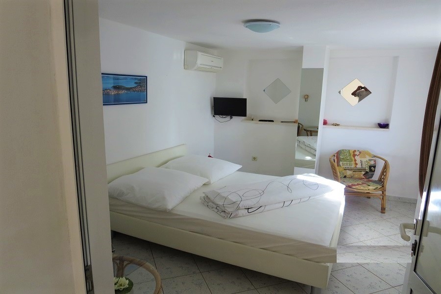 Ložnice s manželskou postelí, klimatizací a světlým nábytkem