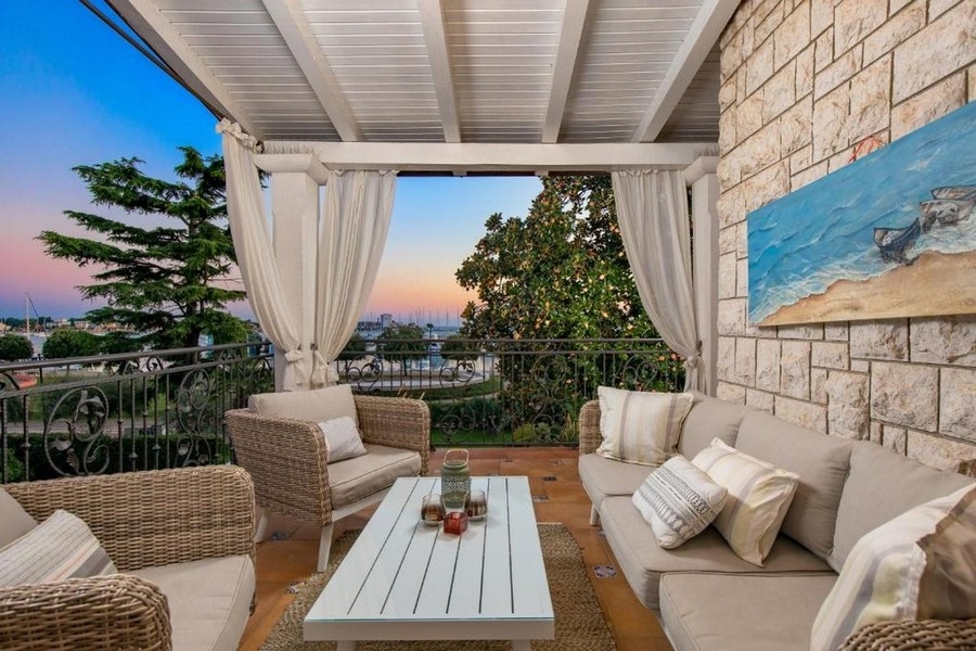 Balkon s obývacím nábytkem a výhledem na moře při západu slunce