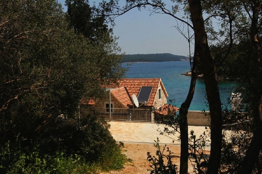 Kamenný dům s výhledem na moře mezi stromy