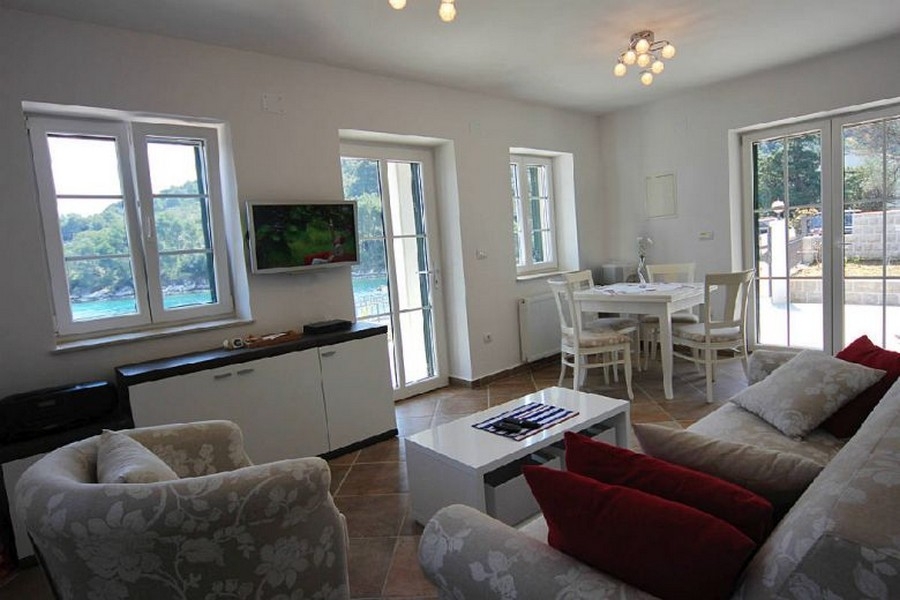 Světlý obývací pokoj s velkými okny a výhledem na moře