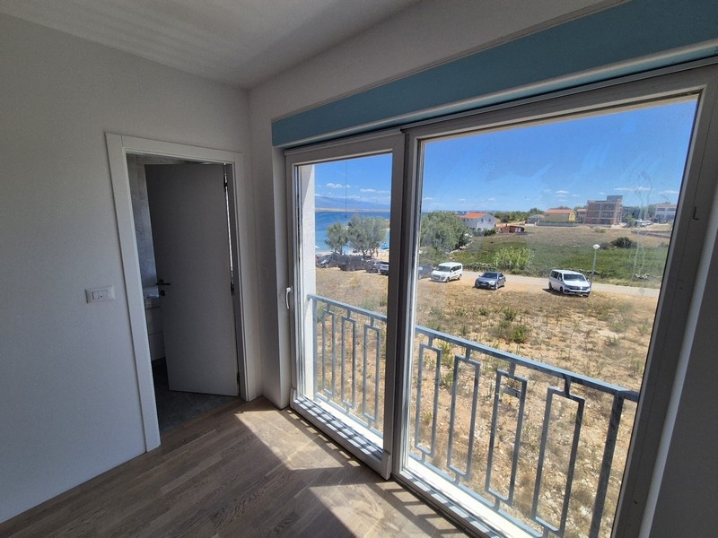 Ložnice s velkými okny a přístupem na balkon s výhledem na moře.