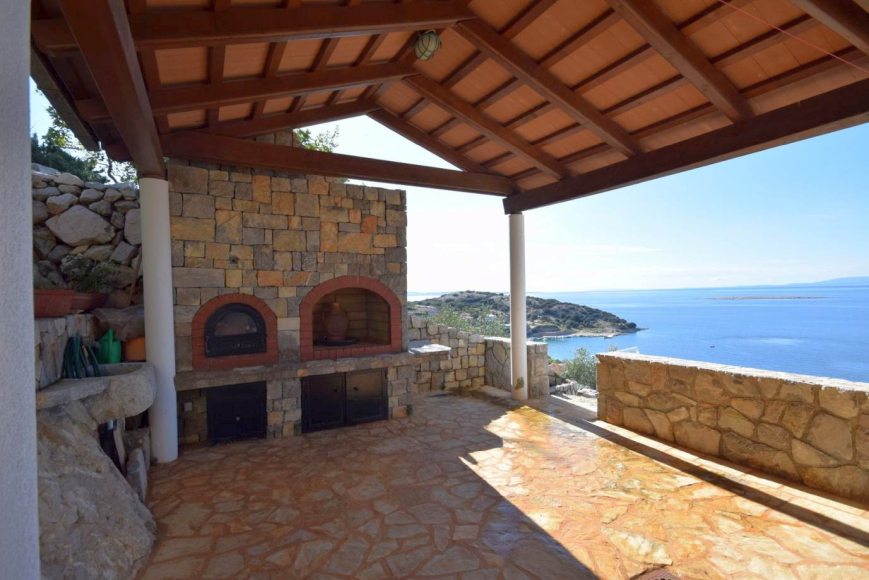 Velká terasa s výhledem na moře a kamennými pecemi.