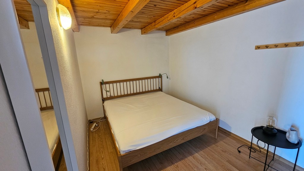 Ložnice s manželskou postelí a trámovým stropem