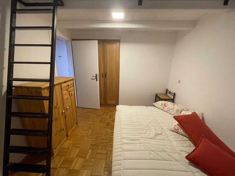 Ložnice s dřevěným nábytkem a žebříkem na galerii