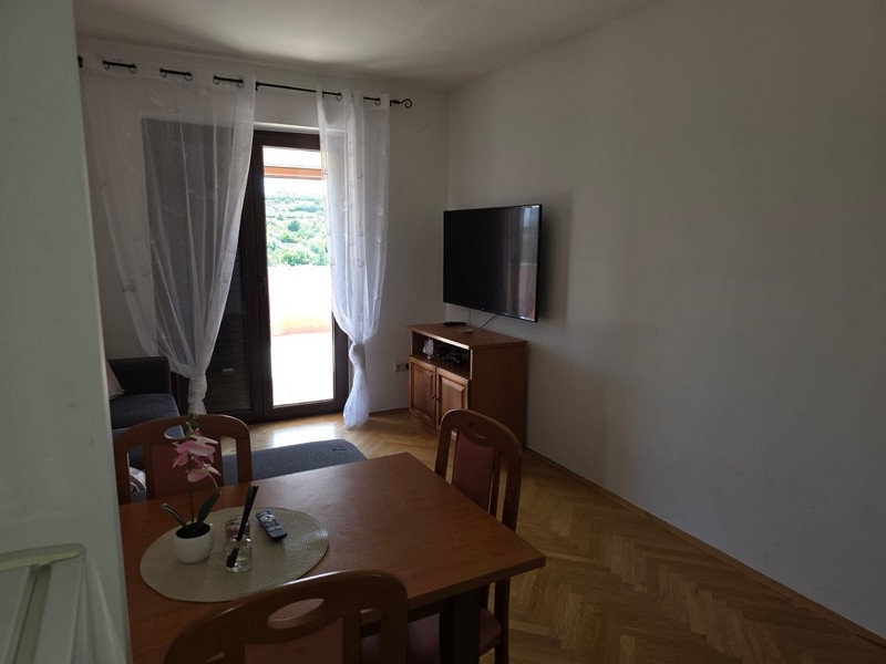 Obývací pokoj se stolem, televizí a dveřmi na terasu