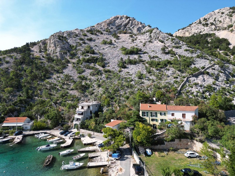 Zátoka s čistou vodou a pohoří Velebit shora