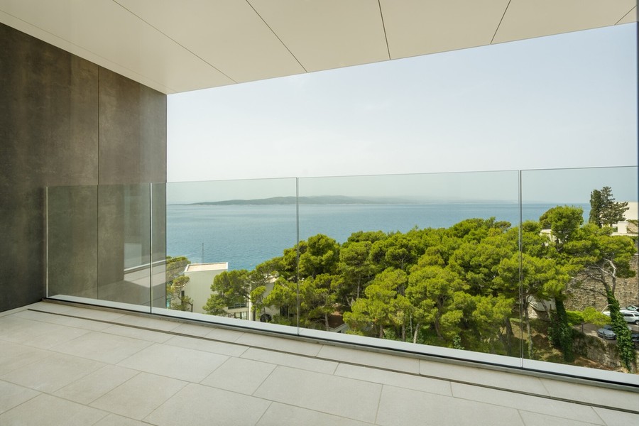 Balkon se skleněným zábradlím a výhledem na moře